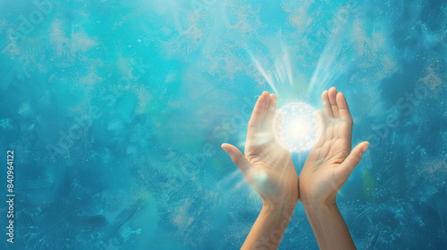 energy healing ball of light cupped between two human hands on blue abstract background with copyspace