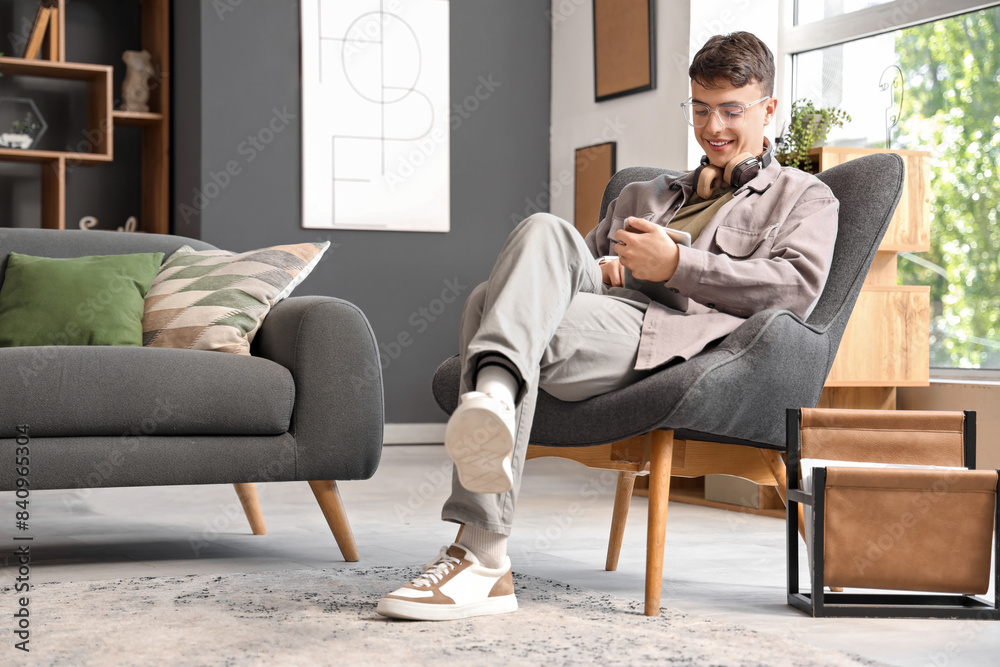 Young man using tablet computer in armchair at home Young man using tablet computer in armchair at home