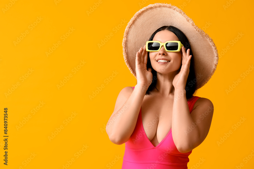 Beautiful young woman in stylish pink swimsuit and sunglasses on yellow background Beautiful young woman in stylish pink swimsuit and sunglasses on yellow background