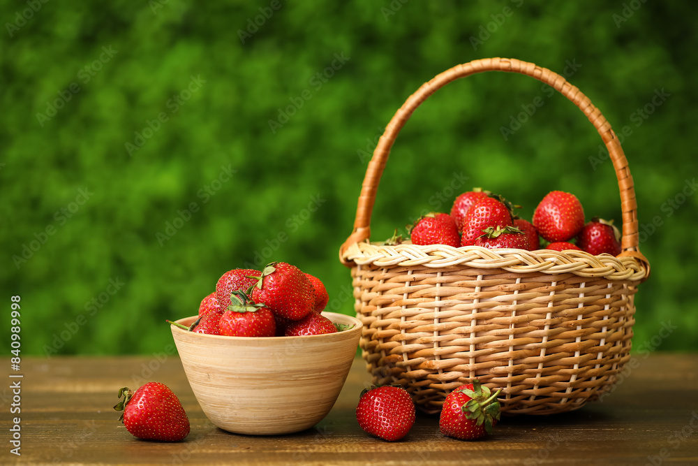 Bowl and wicker basket with sweet fresh strawberries on wooden table outdoors Bowl and wicker basket with sweet fresh strawberries on wooden table outdoors