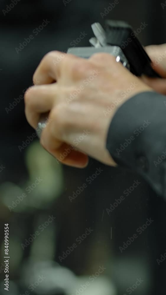 Hairdresser clean his equipment before the arrival of the customer. Close-up of the hands of a professional barber with a brush and trimmer. Vertical shot. Hairdresser clean his equipment before the arrival of the customer. Close-up of the hands of a professional barber with a brush and trimmer. Vertical shot.
