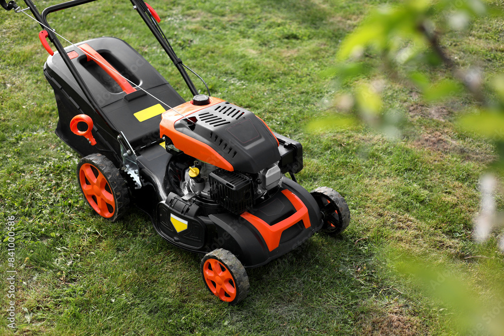 Modern lawn mower on green grass in garden Modern lawn mower on green grass in garden