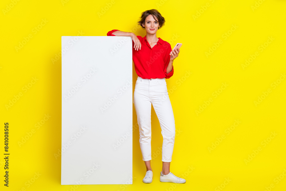 Portrait of good mood adorable girl with bob hairdo dressed red shirt hold smartphone app presentation isolated on yellow color background Portrait of good mood adorable girl with bob hairdo dressed red shirt hold smartphone app presentation isolated on yellow color background