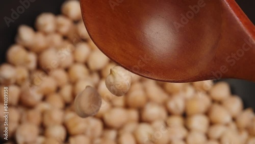  Falling chickpeas from a wooden spoon, capturing motion and detail of the legumes.