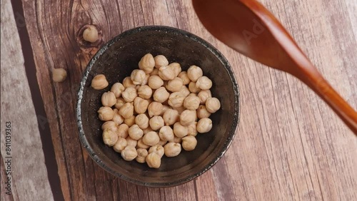  Falling chickpeas from a wooden spoon, capturing motion and detail of the legumes.