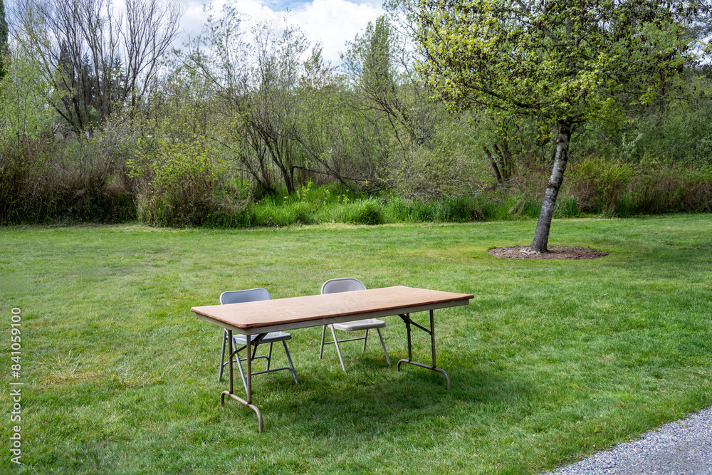 Setting up for a spring festival in a grass field in the park, temporary folding table and two chairs for participant sign in
Setting up for a spring festival in a grass field in the park, temporary folding table and two chairs for participant sign in