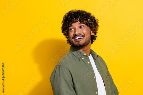 Photo of young hispanic optimistic handsome businessman migrant looking at banner in khaki shirt isolated on yellow color background © deagreez