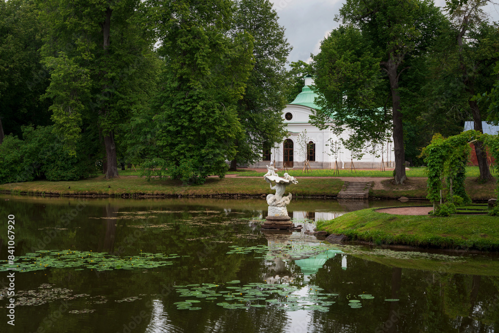 View of the sculpture Triton on the shore of the Chinese Pond in the Oranienbaum Palace and Park Ensemble on a sunny summer day, Lomonosov, St. Petersburg, Russia View of the sculpture Triton on the shore of the Chinese Pond in the Oranienbaum Palace and Park Ensemble on a sunny summer day, Lomonosov, St. Petersburg, Russia