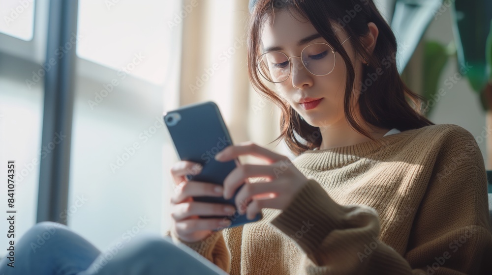 Cropped shot of an young woman using smart phone at home. Smiling woman using smartphone at home, messaging or browsing social networks while relaxing on couch Cropped shot of an young woman using smart phone at home. Smiling woman using smartphone at home, messaging or browsing social networks while relaxing on couch