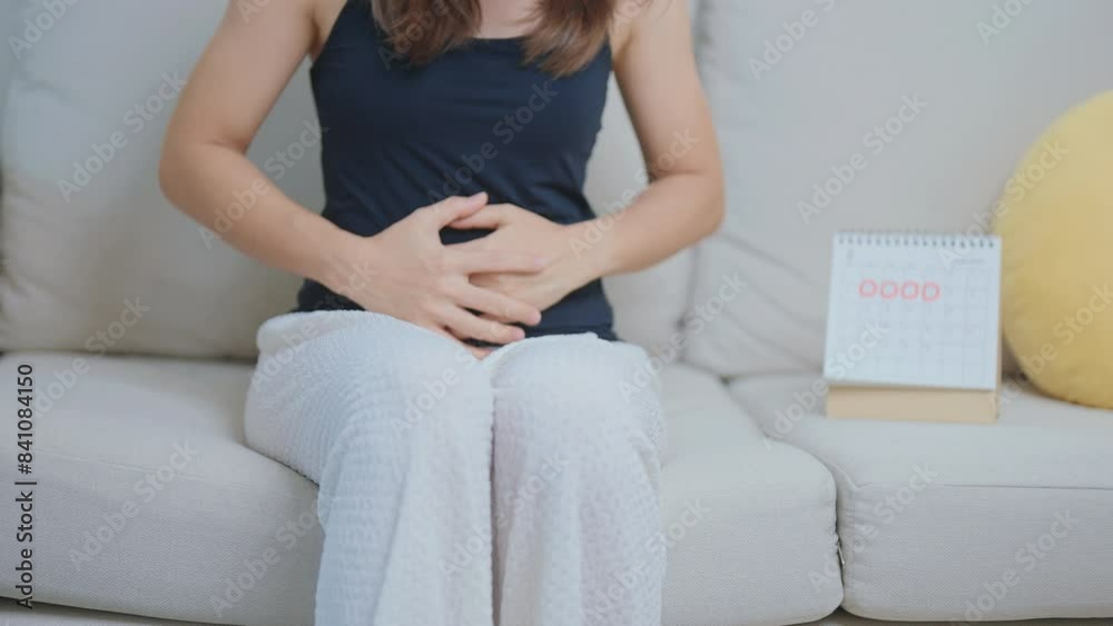 Menstruation period cycle of monthly and Stomachache concepts. woman having abdomen pain with calendar, illness female suffer from premenstrual ache and body Health problem on sofa at home Menstruation period cycle of monthly and Stomachache concepts. woman having abdomen pain with calendar, illness female suffer from premenstrual ache and body Health problem on sofa at home