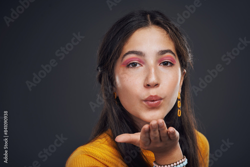 Studio portrait, girl and blowing kiss for love with flirting and romantic confidence. Female teenager, mouth pout and lips emoji or icon with romance for date and playful flirt by dark background