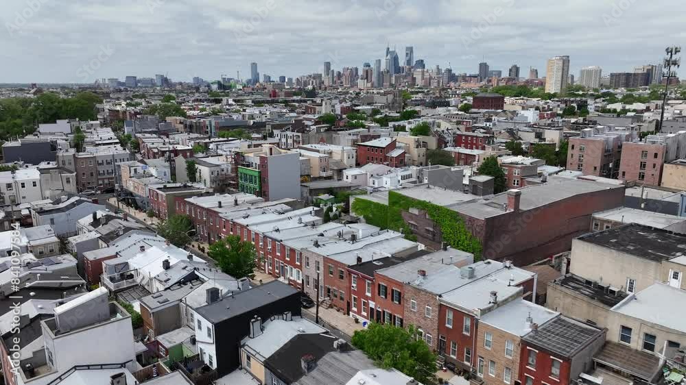 Suburb neighborhood of Philadelphia with skyline in background. Homes and historic buildings in suburbia. Sunny day in spring season. Aerial wide shot.