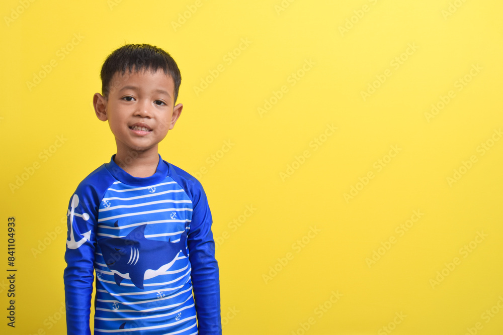 Portrait of a cute little Asian boy wearing a swimsuit isolated on a yellow background. Summer vacation concept. With Copy space Portrait of a cute little Asian boy wearing a swimsuit isolated on a yellow background. Summer vacation concept. With Copy space