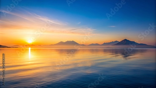 Tranquil sunrise over calm sea with minimalistic mountains in the background  Tranquil  Awakening  Sunrise  Minimalist  Sea