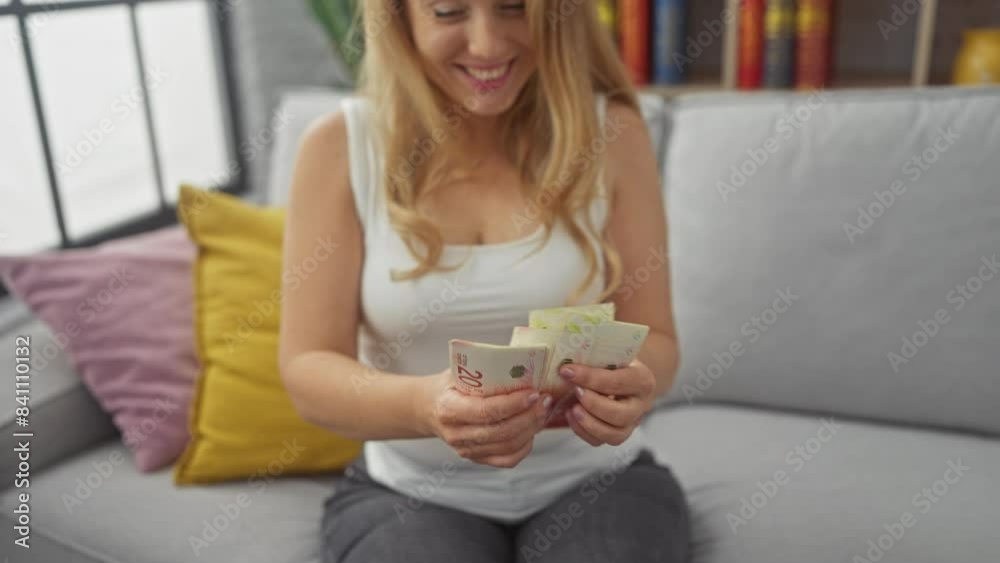 Blonde woman counting shekels indoors, showcasing finance, currency, lifestyle, caucasian, adult, beautiful, money, sofa, livingroom, israel. Blonde woman counting shekels indoors, showcasing finance, currency, lifestyle, caucasian, adult, beautiful, money, sofa, livingroom, israel.