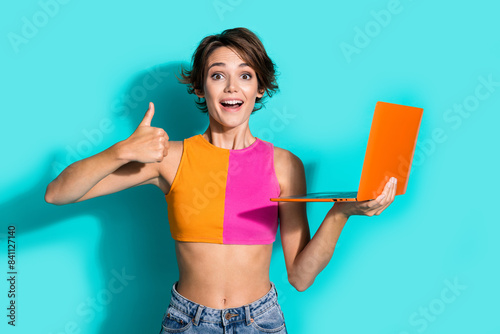 Photo of confident pretty woman wear pink orange top showing thumb up typing modern gadget isolated teal color background