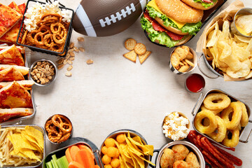 Football snacks table. Game time. Pizza, burger, popcorn, nuts and ball on wooden background.