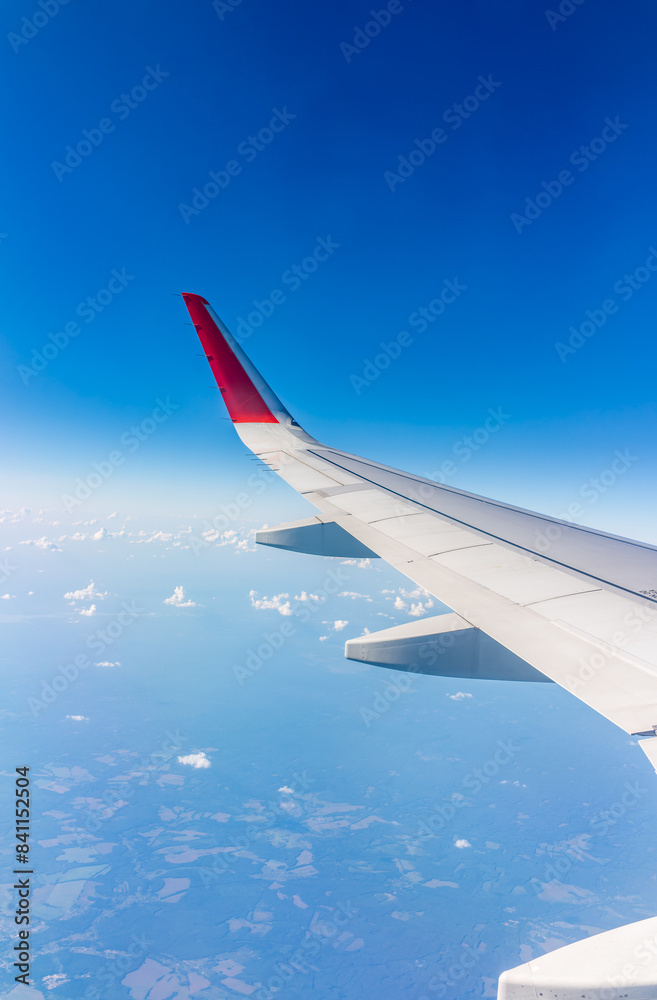 Fototapeta premium View from the airplane window at a beautiful cloudy sky and the airplane wing