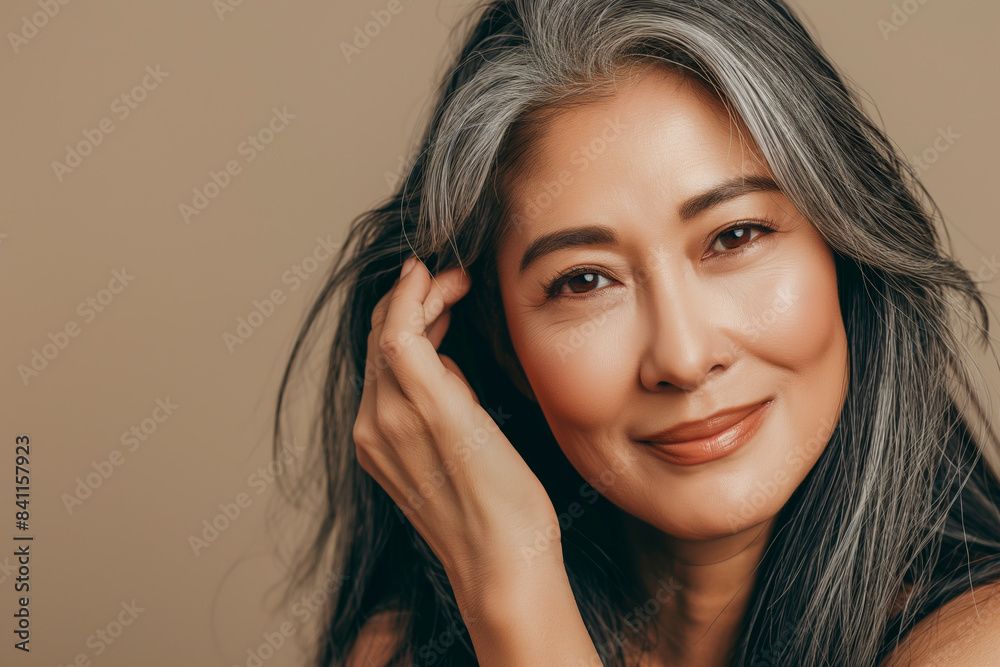 Fototapeta premium Japanese adult woman with smooth healthy face skin. Beautiful aging mature asian woman with long gray hair and happy smiling touch face. Beauty and cosmetics skincare advertising concept.