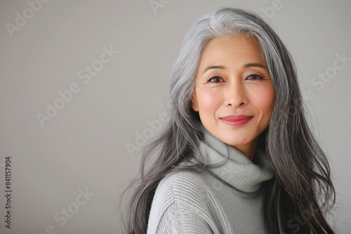 Japanese adult woman with smooth healthy face skin. Beautiful aging mature asian woman with long gray hair and happy smiling touch face. Beauty and cosmetics skincare advertising concept. © MVProductions