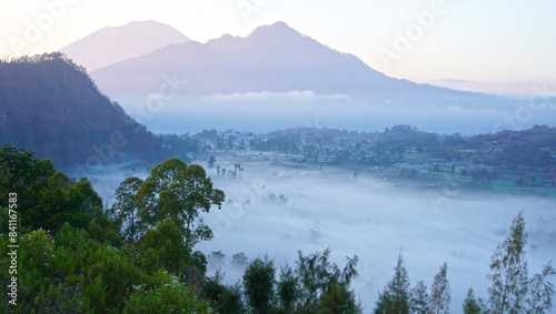 Fog on mountains scenery at sunrise with soft and warm morning light. Natural nature landscape background. Kintamani, Bali.