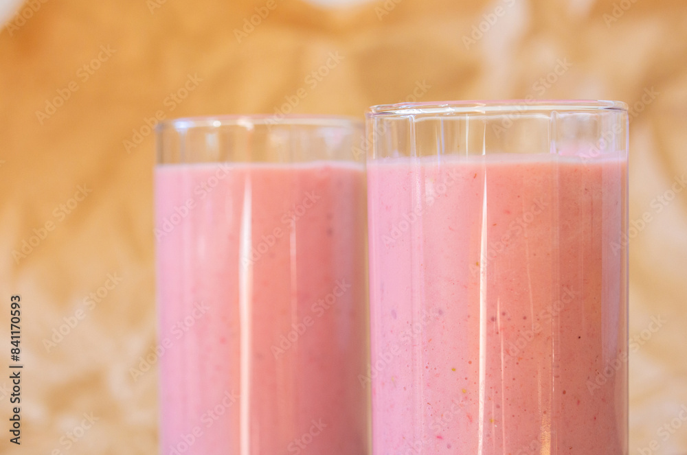 Strawberry fresh pink berry smoothie in two glasses on wooden table