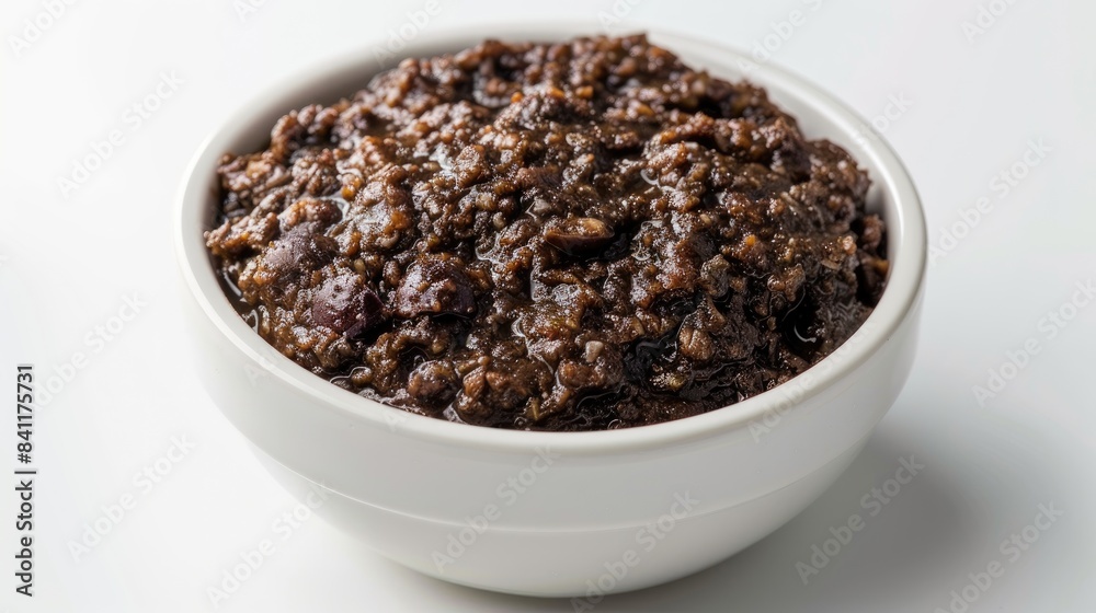 Tapenade made from black olives served in a white bowl on a white background Tapenade made from black olives served in a white bowl on a white background