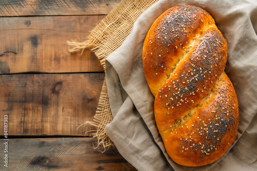 Two Freshly baked Challah bread covered with poppy and sesame seeds, top view on rustic wooden background, traditional festive Jewish cuisine. photo