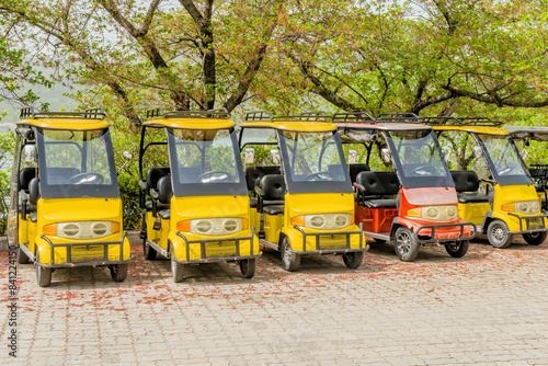 Row of yellow electric tourist carts parked on a paved area under large trees in Suncheon, South Korea