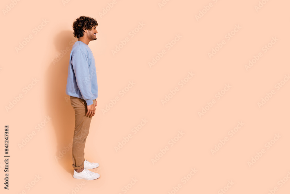 Full size side profile photo of nice guy dressed blue pullover pants look at proposition empty space isolated on pastel color background Full size side profile photo of nice guy dressed blue pullover pants look at proposition empty space isolated on pastel color background
