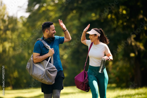 Fototapeta Naklejka Na Ścianę i Meble -  Cheerful athletic couple giving high-five after successful workout in nature.