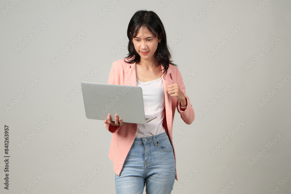 angry upset mad asian woman wearing formal casual outfit holding laptop computer on isolated background. angry upset mad asian woman wearing formal casual outfit holding laptop computer on isolated background.