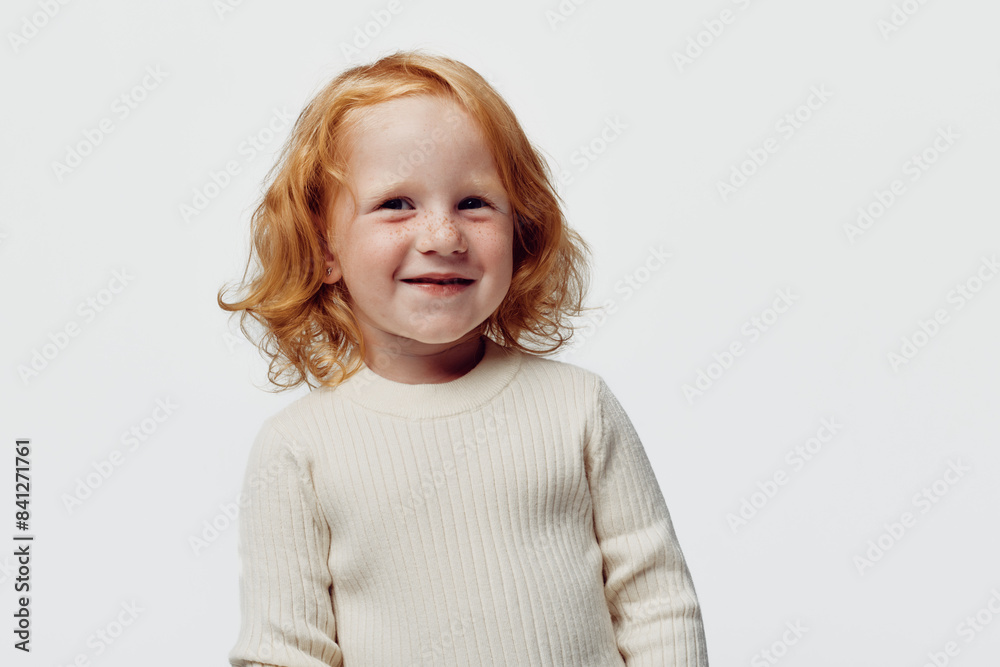 Redhaired girl in white sweater standing against white background innocence and beauty of youth Redhaired girl in white sweater standing against white background innocence and beauty of youth