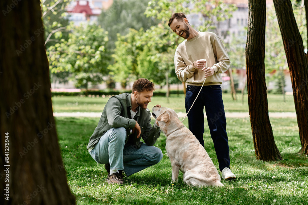 Fototapeta premium A bearded gay couple is enjoying a sunny afternoon in the park with their labrador retriever.
