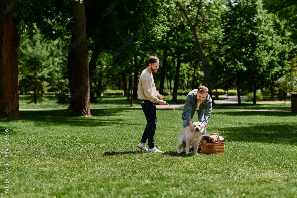 A bearded gay couple spends quality time with their labrador dog in a green park.