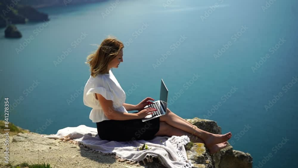 Freelance woman sea. working on a laptop by the sea, typing away on the keyboard while enjoying the beautiful view, highlighting the idea of remote work.