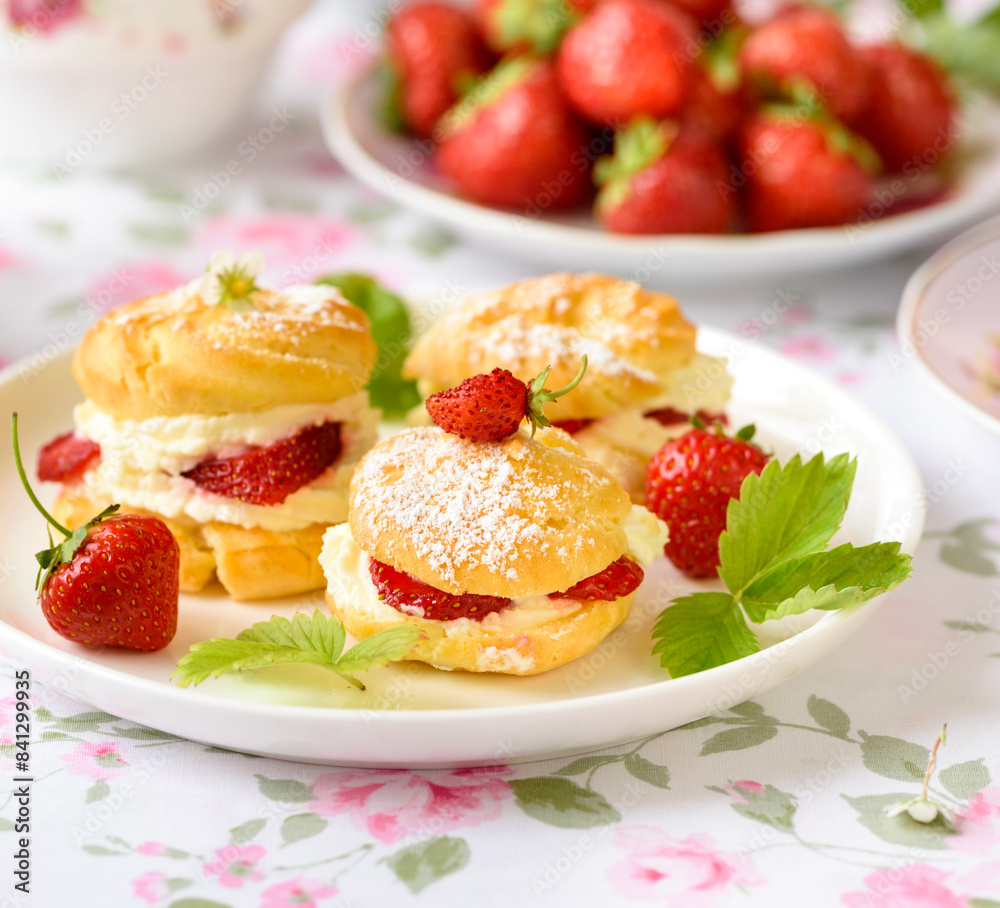 Cream puffs cakes or profiterole filled with whipped cream served with strawberries Cream puffs cakes or profiterole filled with whipped cream served with strawberries