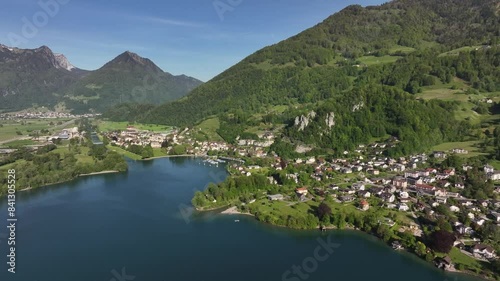 Drone advancing over the picturesque village of Wessen in Switzerland, nestled along the shores of Lake Walensee amidst the Swiss Alps. photo