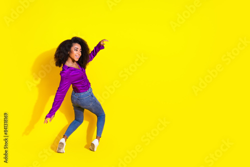 Full body photo of lovely lady look empty space keep balance fall back dressed stylish violet garment isolated on yellow color background