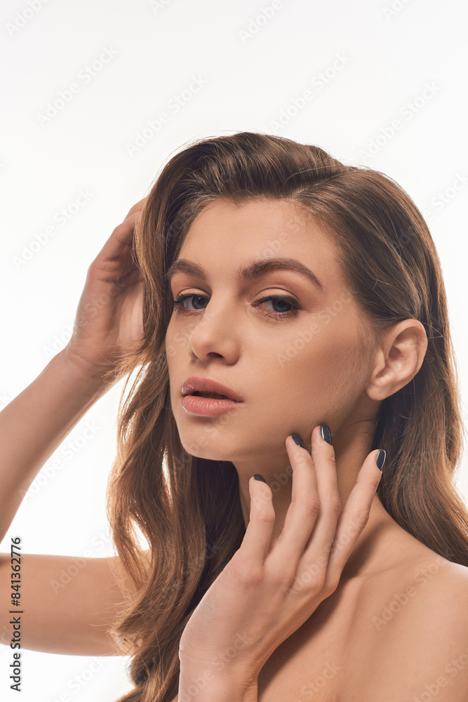 Fototapeta premium A young, beautiful woman with long wavy hair exuding an aura of mystery and allure.