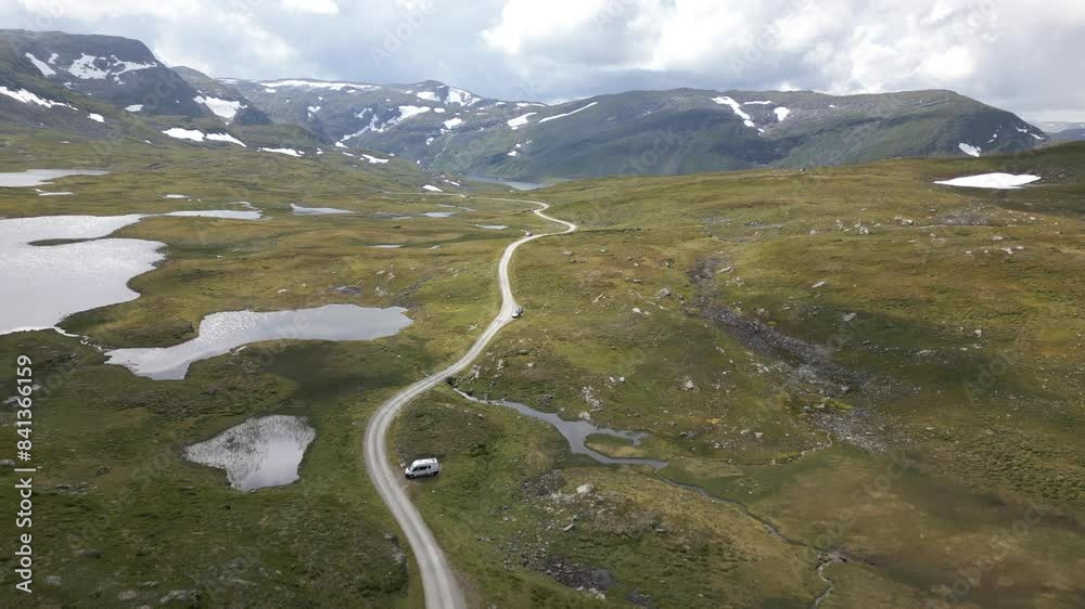 Aerial drone shot following a long gravel trail on top of Vikafjellet in Norway, eventually revealing a large lake on top of the mountain Aerial drone shot following a long gravel trail on top of Vikafjellet in Norway, eventually revealing a large lake on top of the mountain
