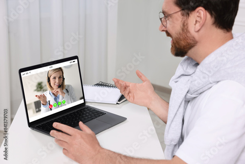 Online medical consultation. Man having video chat with doctor via laptop at table indoors