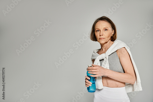 Older woman in comfortable clothing serenely sips from a water bottle. © LIGHTFIELD STUDIOS