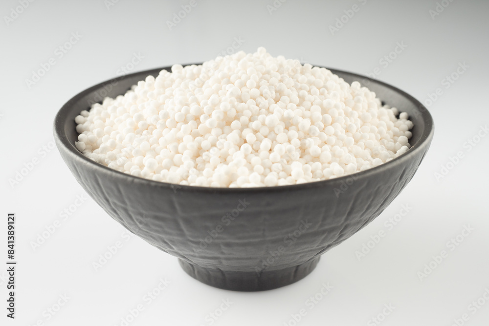 White Sago Pearls in Dark Bowl Also Know as Sabudana, Tapioca Pearl or Sago Seeds isolated on White Background White Sago Pearls in Dark Bowl Also Know as Sabudana, Tapioca Pearl or Sago Seeds isolated on White Background