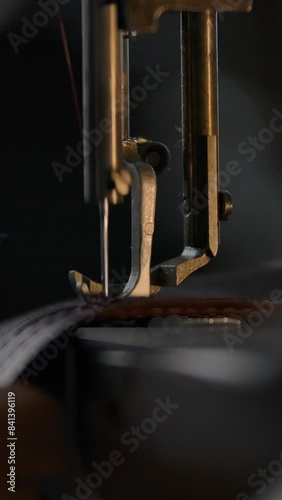 Close-up view of working sewing machine presser foot, stitching in slowmotion. Tailor's hand holding sewing leather carefully. Manufacturing handicraft unique individual bags, belts, accessories