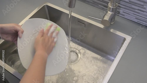 Washing dishes with a sponge in a kitchen sink photo