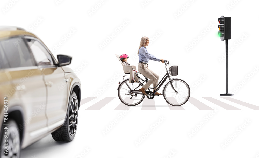 Woman riding a bicycle with a child in a back seat in front of a vehicle at pedestrian crossing