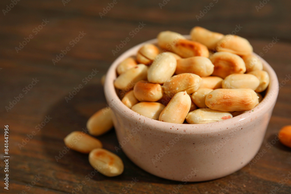 Roasted peanuts in bowl on wooden table, closeup. Space for text Roasted peanuts in bowl on wooden table, closeup. Space for text