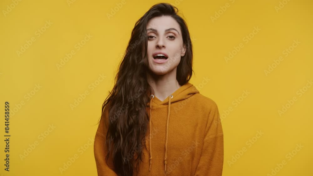 Woman talking on video call against yellow background Woman talking on video call against yellow background