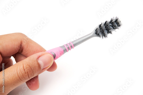 Hand holding old toothbrush that has been used and is worn out isolated on white background. Oral and teeth cleaning equipment.